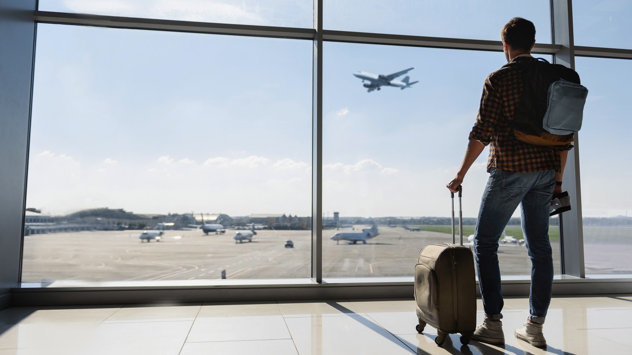 Young man holding his suitcase in the airport; image used for the HSBC International Services Employee Banking Solutions Page.