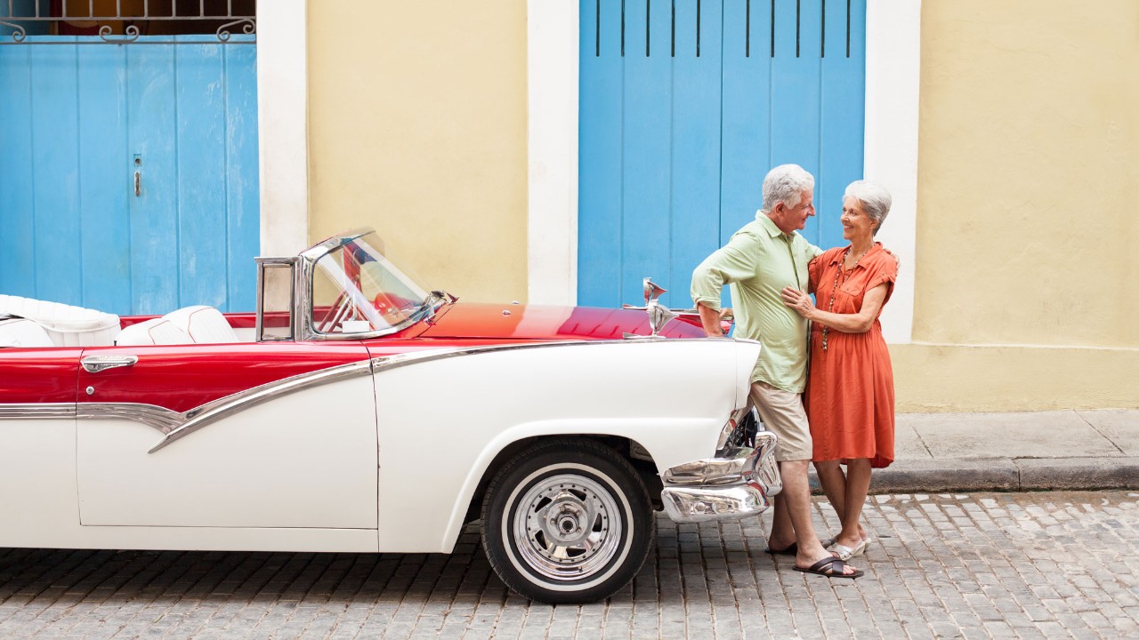 retired couple standing by vintage car