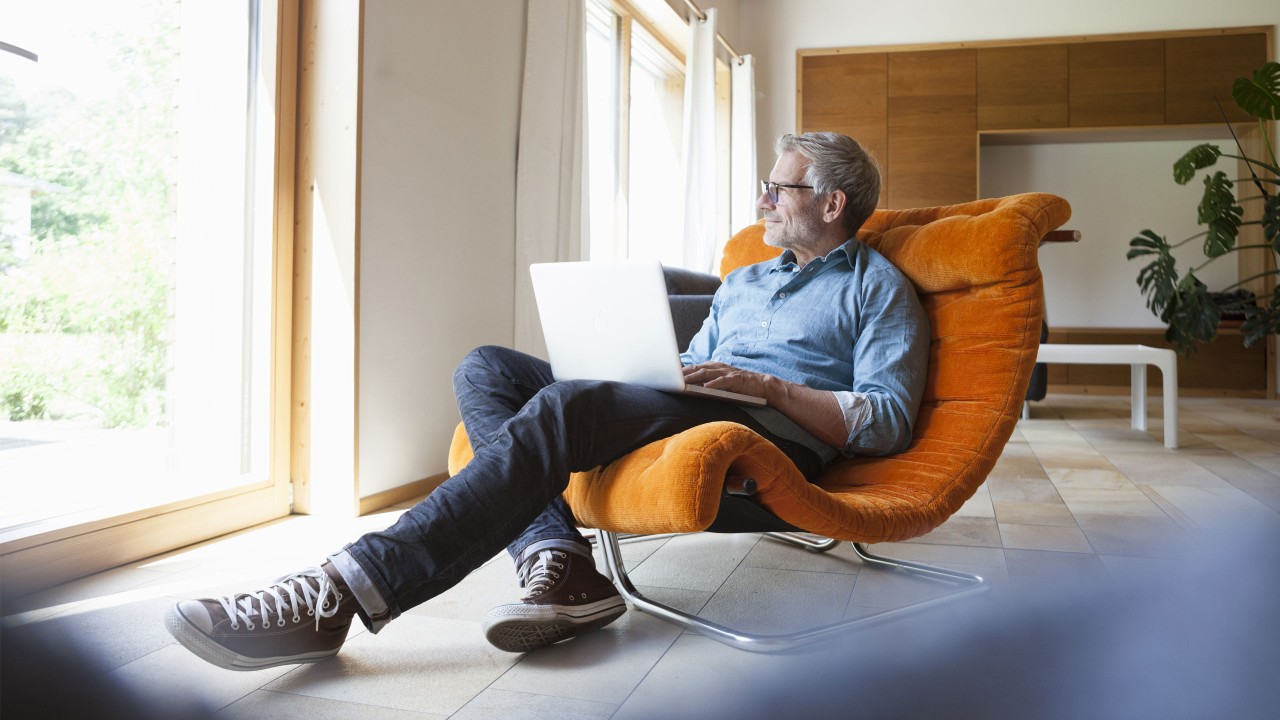 mature man relaxing in comfy chair with laptop; image used for HSBC International Services Life abroad article Setting up your finances
