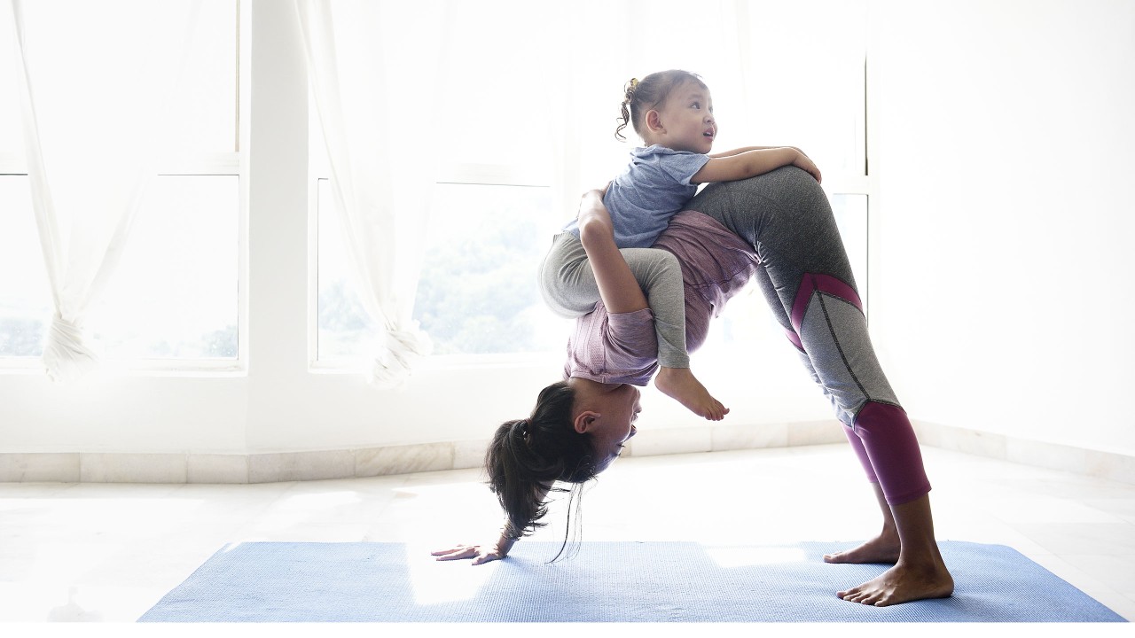 woman exercising at home with baby on her back; image used for HSBC International Services Life abroad article Fitness tips for expats.