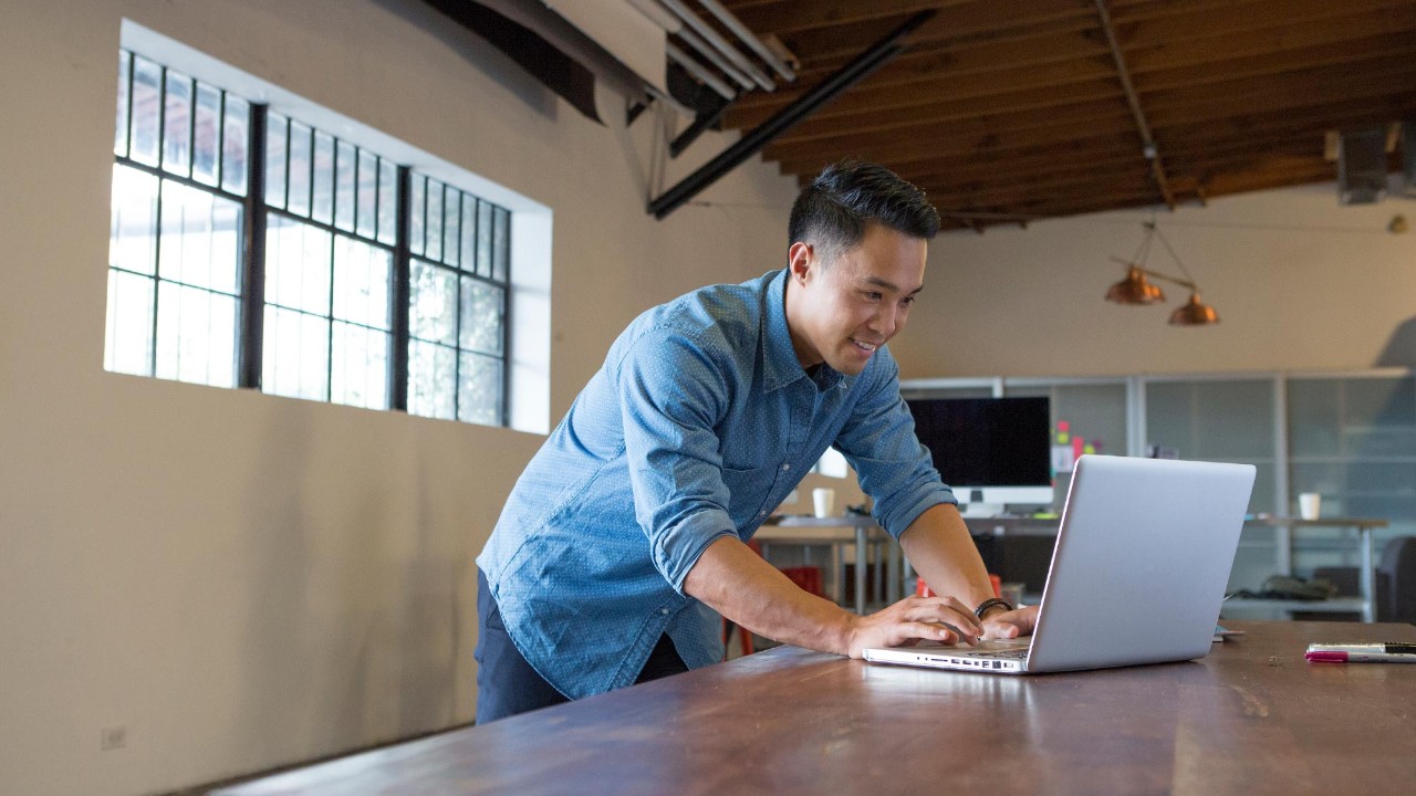 standing man doing work on his laptop; image used for HSBC International Services for Chinese Executives, needing international services